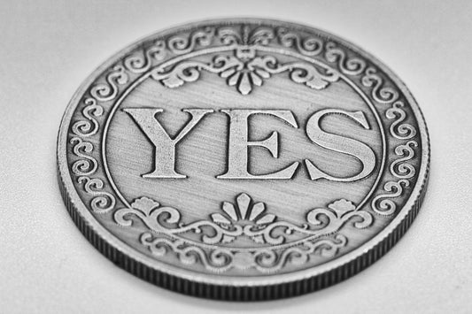 A silver coin with the word yes engraved.