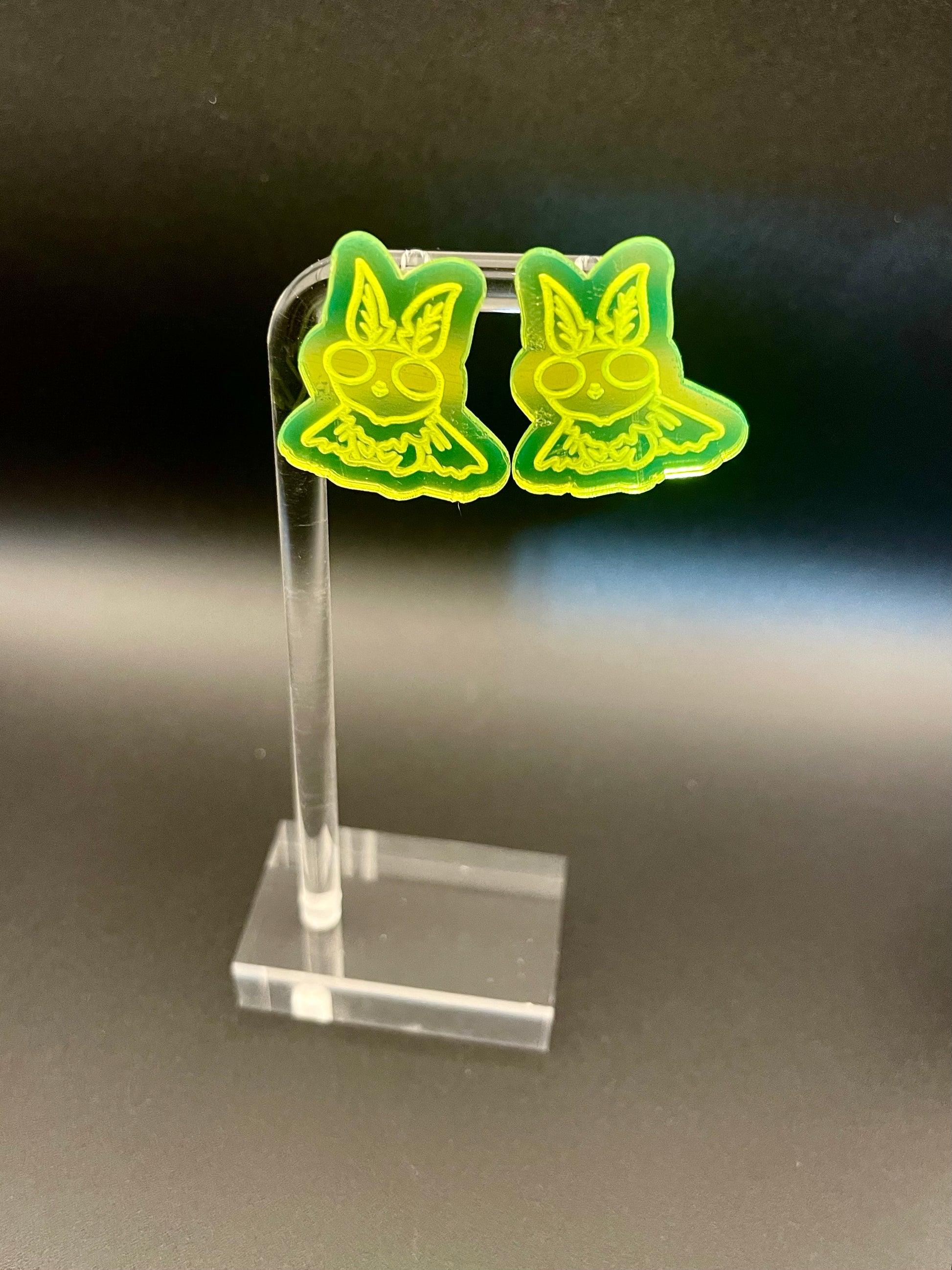 Green mothman earrings dark background
